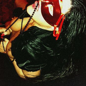 Sandy leckt mit ihrer Zunge an einer schwarzen Perlenkette