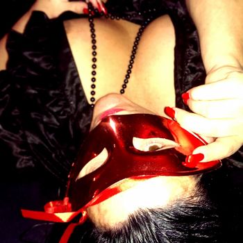 Sandy liegend mit einer schwarzen Perlenkette und einer roten , venezianischen Maske